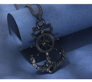 Detail of black nautical anchor and helm pendant necklace on textured blue background