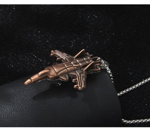 Vue macro détaillée d'un pendentif d'avion de chasse en bronze sur une chaîne argentée