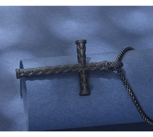 Detailed view of black stainless steel cross pendant with textured woven pattern