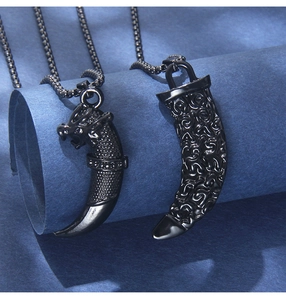 Macro detail of black punk wolf tooth pendant with dragon head and bead chain