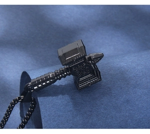 Macro shot of black Mjölnir pendant with intricate Norse carvings and textured chain