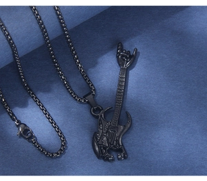 Close-up of black stainless steel guitar necklace with rock sign pendant on blue surface