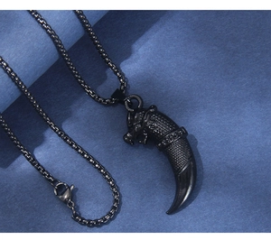 Close-up of black punk dragon head pendant with textured fang on a metal box chain