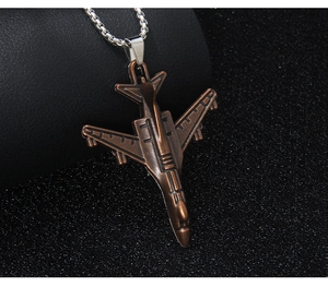 Gros plan d'un pendentif d'avion de chasse en bronze vintage sur une chaîne argent