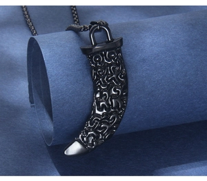 Macro shot of black wolf tooth pendant with ornate patterns on a blue textured background