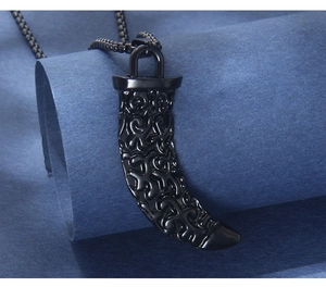 Detail of black wolf tooth pendant with engraved patterns on stainless steel chain
