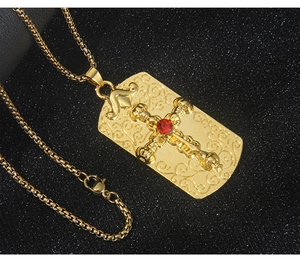 Détail macro du pendentif croix dorée avec pierre rouge et motifs de relief floraux fins
