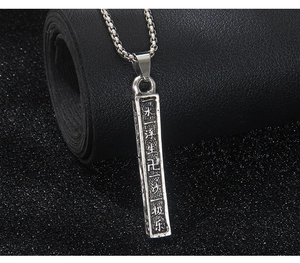 Vue détaillée du pendentif pilier en acier vintage avec écritures bouddhistes gravées