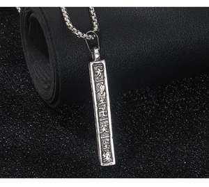 Détail macro du pendentif rétro en acier inoxydable avec inscriptions Zen et chaîne carrée