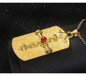 Gros plan du pendentif carré doré avec croix en cristal rouge et gravures ciselées