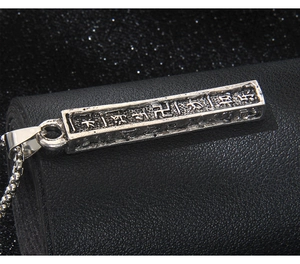 Détail macro du pendentif rectangulaire en acier inoxydable vintage avec gravures