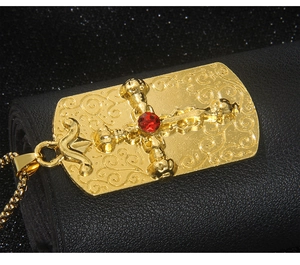 Détail du collier croix dorée avec pierre rouge et motifs gravés de style vintage