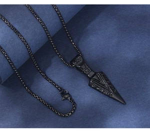 Close-up of black stainless steel arrowhead pendant necklace with engraved rune patterns