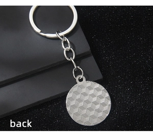 Detail of the silver keychain back showing a geometric isometric cube grid pattern