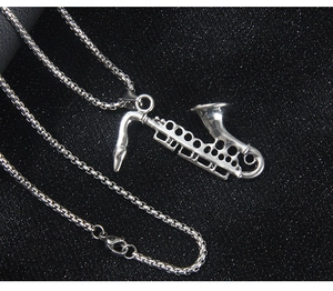 Macro shot of silver saxophone pendant with classic box chain on black glitter surface