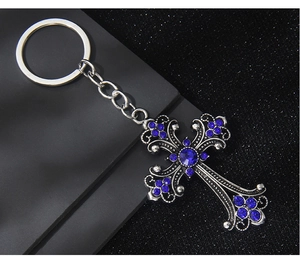 Macro shot of retro silver cross keychain featuring deep blue rhinestones and metal texture