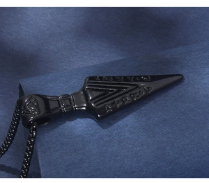 Detail of black stainless steel kunai pendant with Nordic runes and textured surface