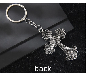 Macro shot of retro silver cross keychain showing polished metal texture and floral details