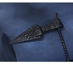 Macro detail of black stainless steel Viking arrow pendant with Nordic runes engraving