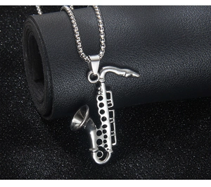 Detailed macro view of a silver saxophone pendant with polished stainless steel chain