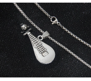 Gros plan du collier pendentif Pipa rétro avec chaîne box sur tissu noir