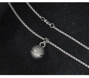 Detailed macro view of a 3D basketball pendant on a silver box chain necklace