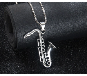 Macro view of silver saxophone pendant with polished box chain on black texture
