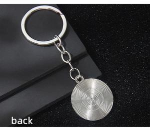Silver metal keychain detail showing back view with intricate radial texture engraving