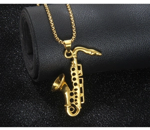 Macro shot of detailed golden saxophone pendant on beaded chain with black leather background
