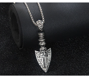 Nahaufnahme des Vintage-Silberschild-Anhängers mit Kreuz auf schwarzem Leder