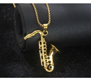 Detail of a vintage golden saxophone pendant necklace with a polished box chain on a dark scroll