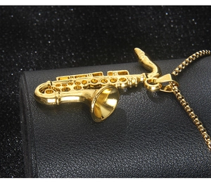 Macro shot of detailed golden saxophone pendant on box chain with mirror polished finish