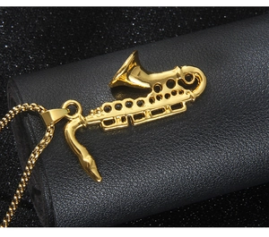 Close-up of golden saxophone pendant necklace on black leather surface with starlight bokeh