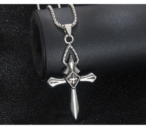 Détail du pendentif croix en argent avec chaîne à perles carrées sur support en cuir