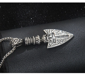 Makroaufnahme von Retro-Edelstahl-Pfeilspitzenanhänger mit Kreuz und Gravurtexturen
