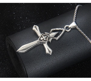 Détail du pendentif croix argentée vintage avec relief X sur cuir noir