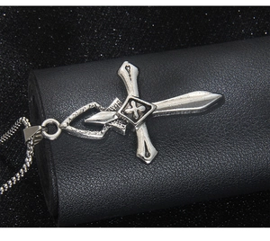 Détail macro du pendentif croix vintage en argent vieilli sur cuir noir texturé