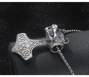 Vue macro du pendentif marteau Mjölnir viking avec tête de loup et chaîne en acier