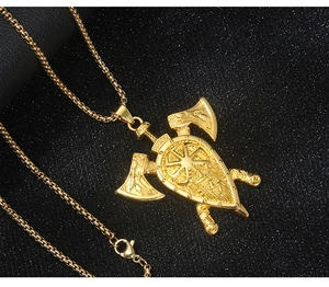 Gros plan d'un pendentif bouclier Viking doré avec haches et symbole Kolovrat