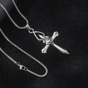Collier croix argentée vintage pour homme avec chaîne box sur fond noir texturé