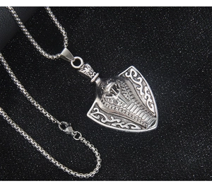 Detailed macro view of a silver stainless steel shield pendant with an Egyptian cobra relief