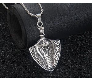 Macro view of shield pendant with embossed king cobra on a vintage silver box chain