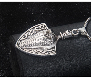Detailed close-up of a vintage steel shield necklace featuring an embossed cobra snake design