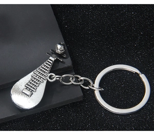 Detailed close-up of a silver metal pipa lute keychain on a textured black background