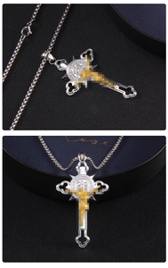 Vue détaillée du pendentif croix en acier bicolore et sa chaîne dans un coffret cadeau