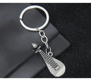Macro detail of silver metal pipa keychain showing strings and fretwork texture