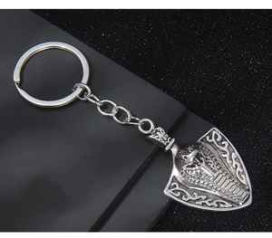 Close-up of vintage cobra shield keychain with detailed celtic engravings on black background