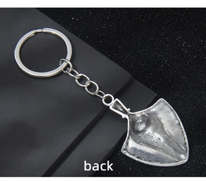 Macro view of the shovel-shaped metal keychain showing vintage silver back texture