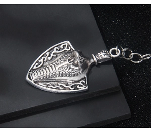 Close-up of retro shield-shaped keychain with embossed serpent design and antique finish