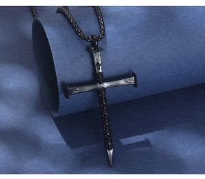 Detail eines schwarzen gotischen Kreuzanhängers mit Totenkopfreliefs und Box-Kette